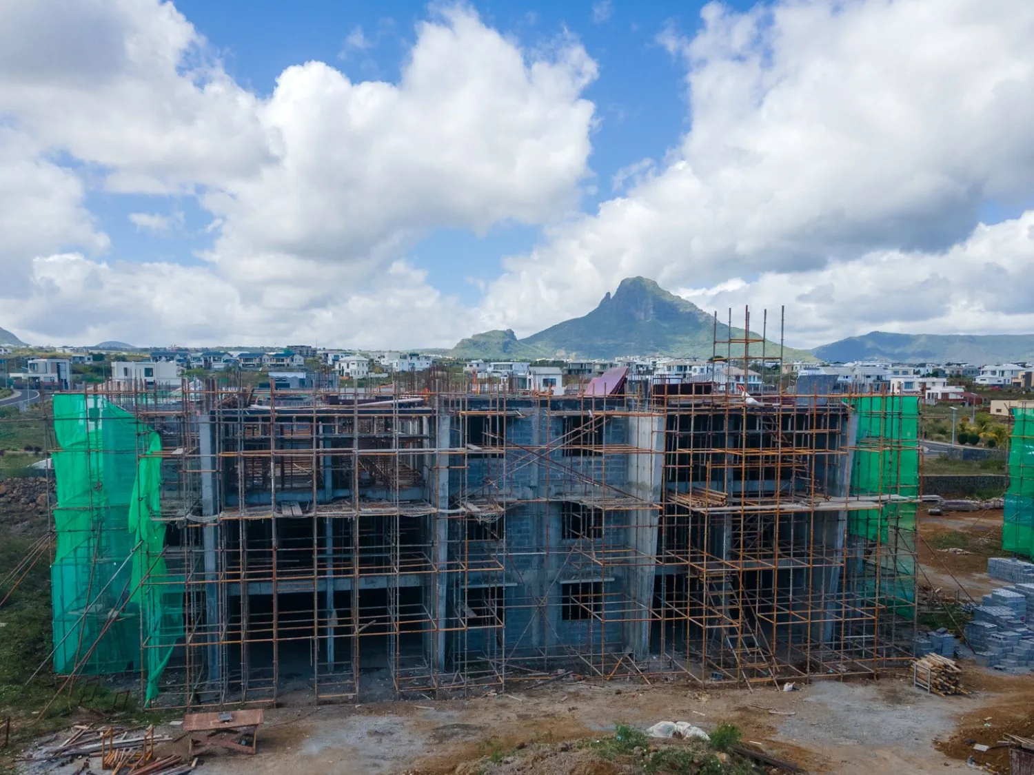 The concrete frame of an Anna City block rising against the Trois Mamelles peaks, September 2026