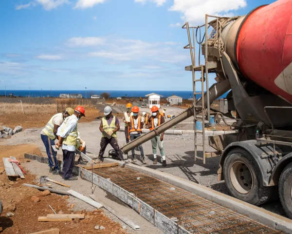 Construction team directing a concrete pour on the Anna City site with the ocean behind